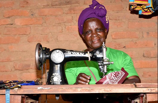Chrissy smiles while seated behind her sewing machine in Malawi.