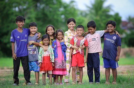 Nine boys and girls are smiling in Cambodia.