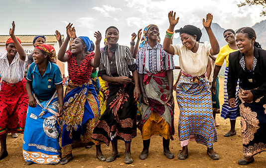 Women savings group members in Malawi celebrate outside a World Vision community center.