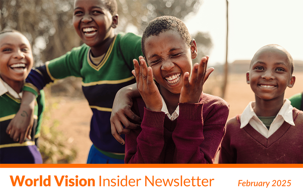 Four children laugh together while playing outside.