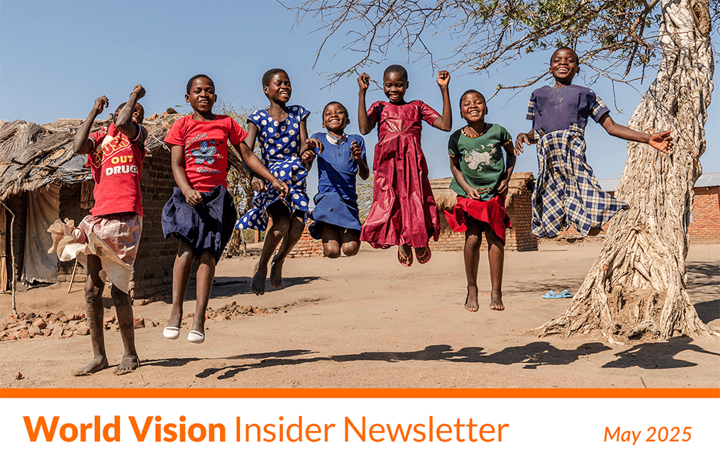 A group of children smile widely and jump.