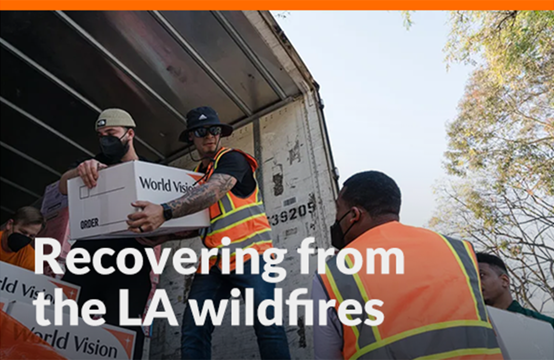Men in reflective vests unload World Vision boxes from a truck.