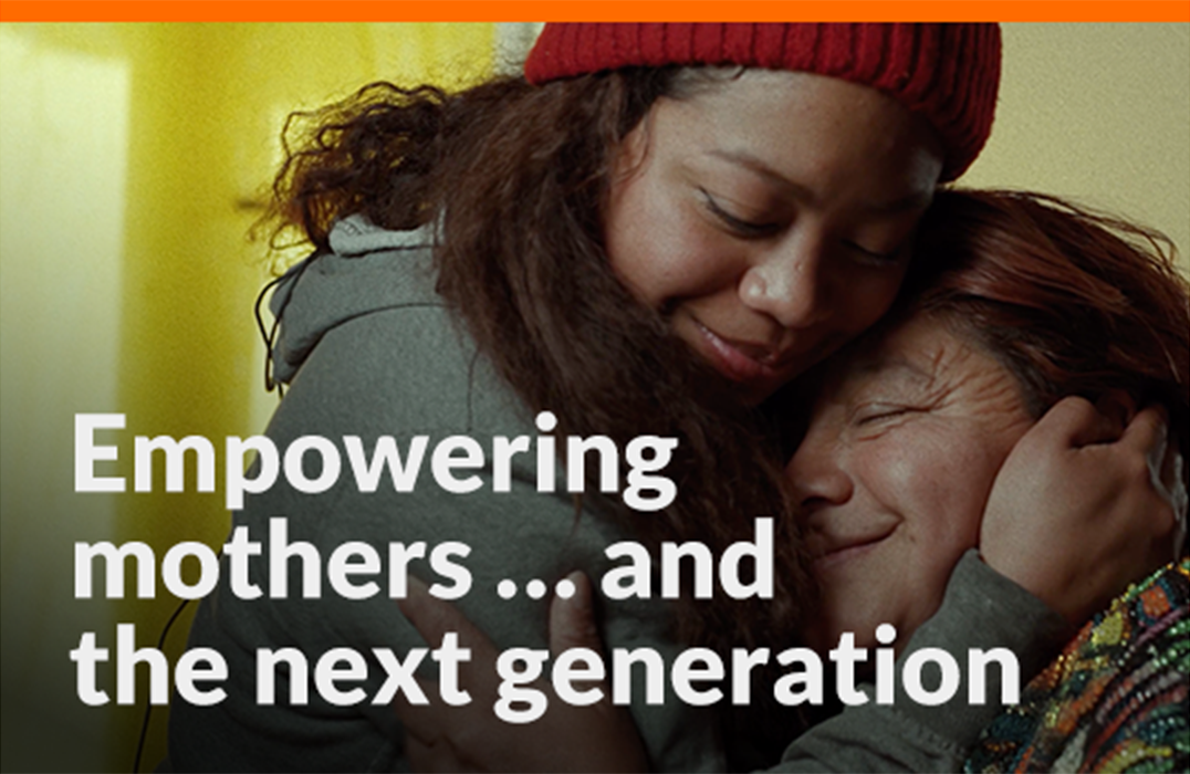 A young woman and older woman smile and hug.