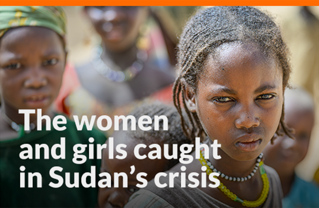 A girl with a child on her back looks intently at the camera. Other children are in the background.