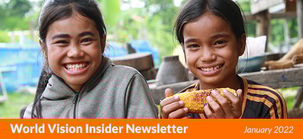 Two smiling Laotian girls eat corn