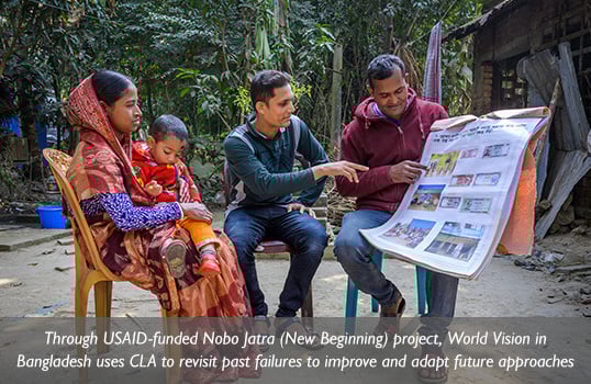 A World Vision staff member in Bangladesh reviews a disaster planning chart with a couple and their child