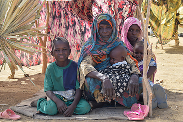 A Sudanese refugee family sits under a makeshift shelter in a transit site on Chad’s eastern border. 