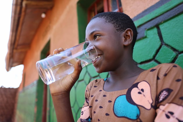 WV527647A young girl smiles while drinking a glass of clean water. 