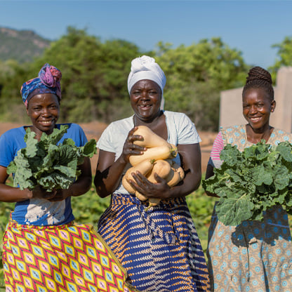 three women holding veggies