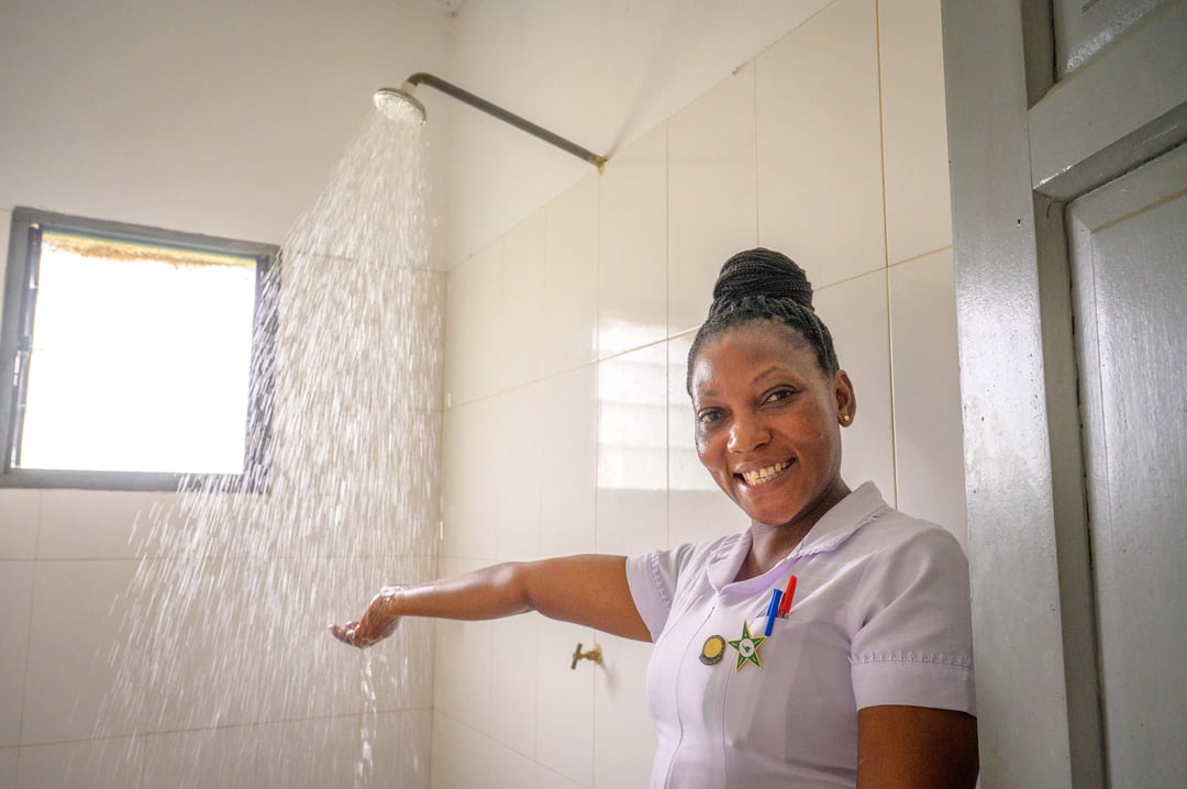 A woman smiles as she shows off a running shower.