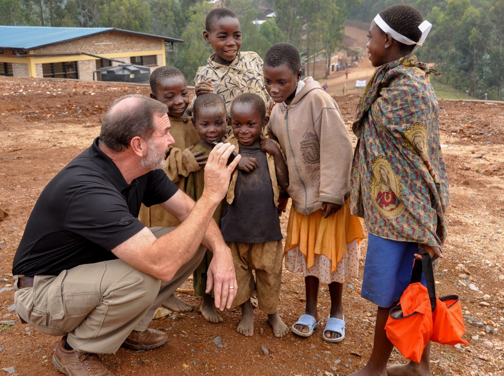 Stu playing with children in front of the new vocational center in Rwanda