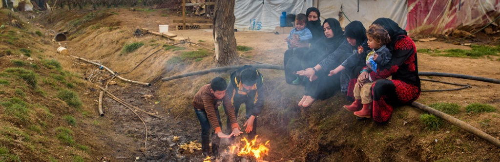 A Syrian refugee family in Lebanon warms themselves by a fire in a ditch in front of their tents, burning garbage -- mostly plastic -- to stay warm. 